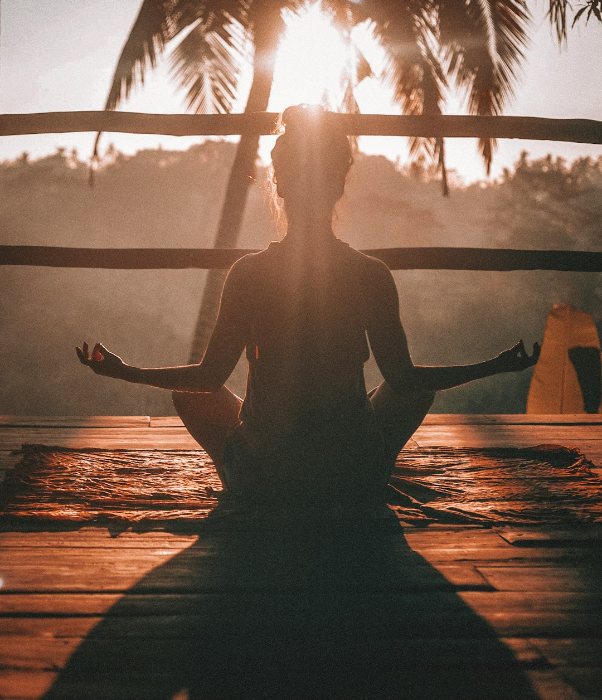 Woman sitting in a yoga pose outside with sunrise