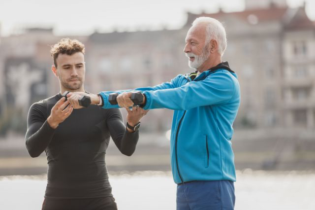 Young man helping older man with exercise