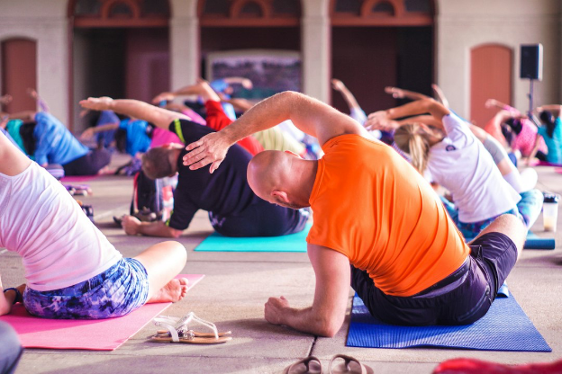 People in a class sitting on yoga mats stretching 