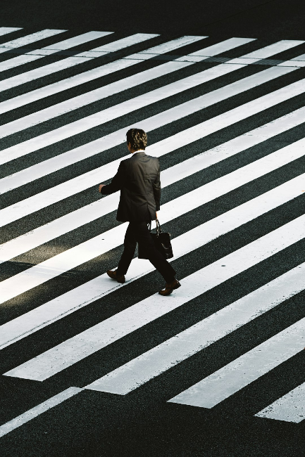 Man in suit and briefcase walking across black and white striped concrete