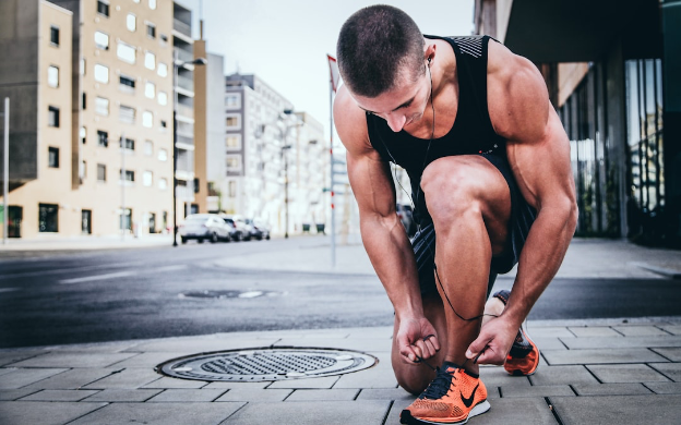 Man kneeling to tie shoe lace on a city sidewalk 