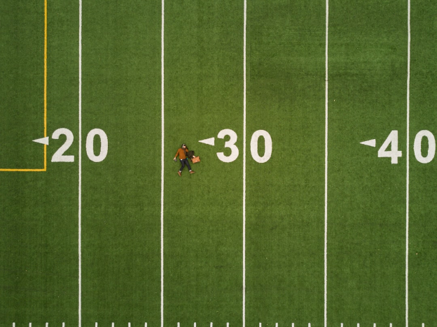 Person lying down at 30 yard line in a football field 