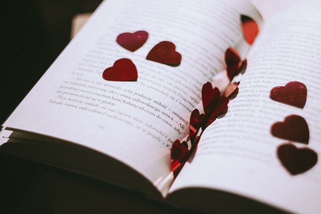 Open book with little plastic red hearts spread on top