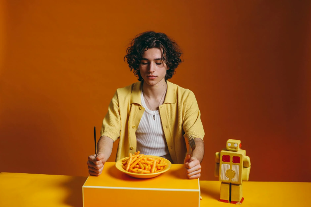 Man thinking about eating a plate of French fries with a fork and knife