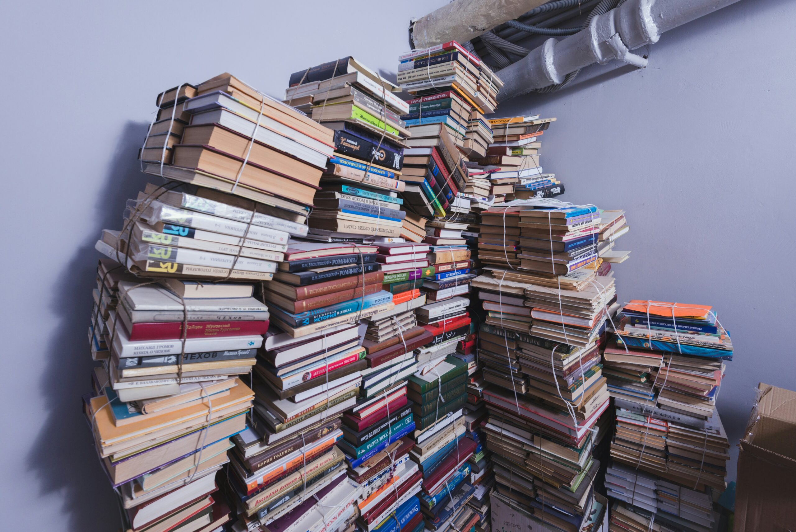 Large stack of books in the corner of a room