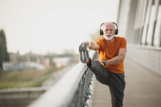 Middle-aged man stretching with headphones on
Smiling senior man enjoying a stretching session with headphones, outdoors on a sunny day