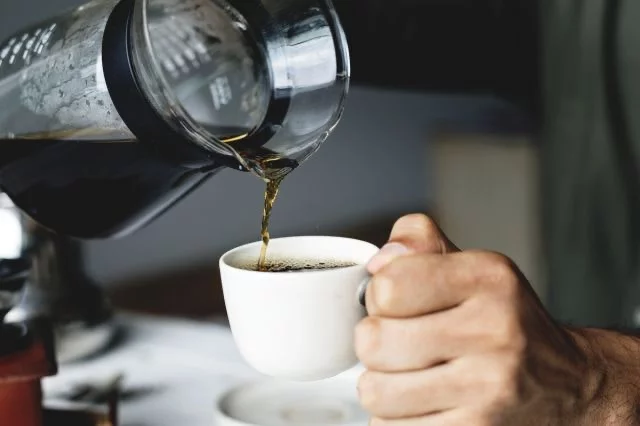 Black coffee being poured into a coffee cup